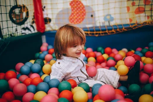 pexels-photo-27175474-27175474 A cheerful child enjoying playtime in a colorful indoor ball pit.